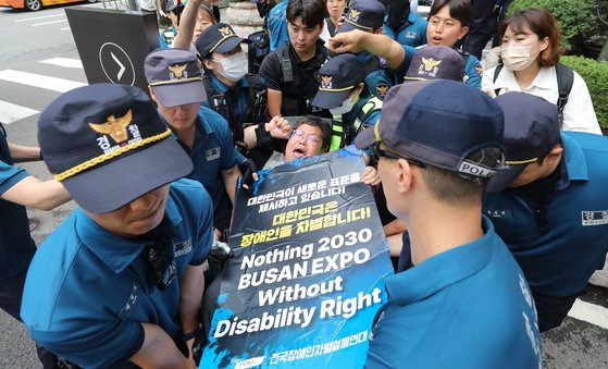 전국장애인차별철폐연대(전장연)이 지난 12일 서울 중구 롯데호텔 지하주차장 출구에서 한덕수 국무총리와의 면담을 요청하며 시위를 벌이자 경찰이 휠체어를 탄 한 전장연 회원을 통행로 밖으로 들어 옮기고 있다. 한 총리는 이날 같은 장소에서 열린 정보보호의 날 기념식에 참석했다. 뉴스1