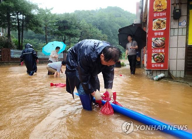 도로까지 차오른 빗물 (군산=연합뉴스) 14일 전북 군산시 구암동 한 상가 건물 인근 도로가 이틀째 내린 집중호우로 침수돼 공무원과 주민들이 배수 작업을 하고 있다. 2023.7.14 [독자 제공. 재판매 및 DB금지] jaya@yna.co.kr