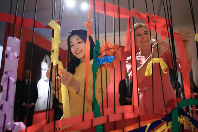 윤석열 대통령과 폴란드를 공식 방문 중인 김건희 여사가 13일(현지시간)  프리다 칼로 전시가 열리는 바르샤바의 와지앤키 박물관에서 프리다 칼로의 시그니처 색상을 사용해 리본을 만드는 체험을 하고 있다. 대통령실제공