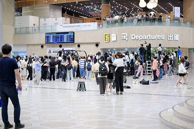 카메라를 든 보이넥스트도어 팬이 3층 출국장 위 4층 식당가 난간에 매달려 사진을 찍고 있다.
