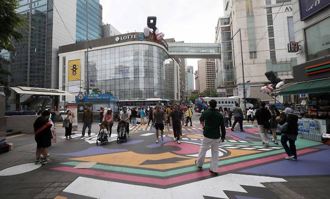 중소기업중앙회의 '백화점·대형마트 유통거래 실태조사'에 따르면 주요 백화점 5곳의 특약매입·임대을 거래시 입점업체가 부담하는 판매수수료율은 평균 21.3%로 집계됐다. 서울 중구 명동거리에서 관광객들이 대규모 바닥화로 꾸며진 거리를 오가고 있다.  /사진=뉴시스