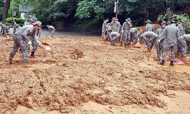 전북 군산시 구암동 산비탈면 토사가 집중호우로 유실되자 군부대원들이 16일 도로에 쌓인 흙더미를 치우고 있다. 군산시 제공