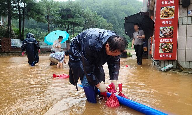 지난 14일 전북 군산시 구암동 한 상가 건물 인근 도로가 이틀째 내린 집중호우로 침수돼 공무원과 주민들이 배수 작업을 하고 있다. 연합뉴스