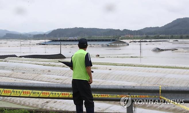 물에 잠긴 동네 바라보는 주민 (청양=연합뉴스) 강수환 기자 = 16일 오후 전날 밤부터 배수장 인근 지천 제방 붕괴로 물이 범람하며 물에 잠긴 충남 청양군 청남면 일대를 동네 주민이 바라보고 있다. 군은 이날 0시 2분께 '청남면 대흥 배수장 인근 지천 제방 붕괴가 의심스러운 상황'이라며 인근 주민들에게 긴급 대피하라는 안전 안내 문자를 발송했다. 2023.7.16 swan@yna.co.kr