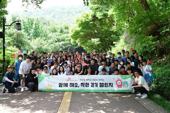 SK엠앤서비스 박정민 대표(가운데 빨간 깃발)와 구성원이 7일 남산 둘레길 착한 걷기 행사의 기념촬영을 하고 있다. (SK엠앤서비스 제공)