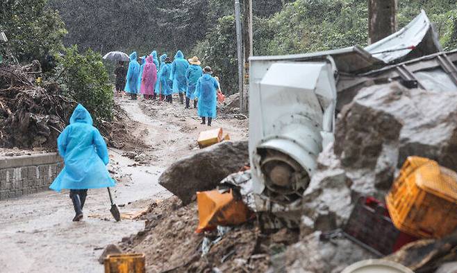 18일 경북 예천군 감천면 벌방리에서 우비를 입은 자원봉사자들이 수해 복구를 위해 진흙밭이 된 길을 걸어 올라가고 있다. 예천=연합뉴스