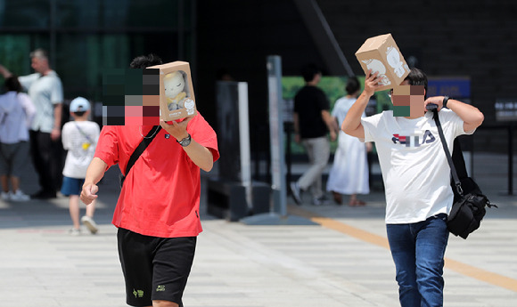 외국 관광객들이 기념품으로 햇빛을 피하고 있다. [사진=뉴시스]