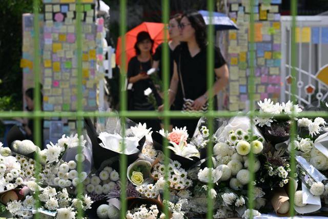 21일 서울 서초구 서이초등학교에서 스스로 목숨을 끊은 초등학교 교사를 추모하는 시민들이 조화를 들고 학교로 들어서고 있다. 최주연 기자