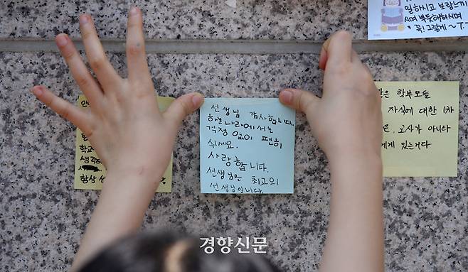 한 어린이가 21일 지난 18일 학교에서 극단적 선택을 한 교사가 재직한 서울 서초구의 한 초등학교 강당 외벽에 해당 교사를 추모하는 메시지를 붙이고 있다.