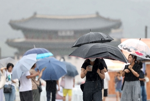 서울 전역에 호우주의보가 발효된 지난 23일 오전 서울 광화문광장에서 시민들이 우산을 쓴 채 걸어가고 있다. [사진 출처 = 연합뉴스]