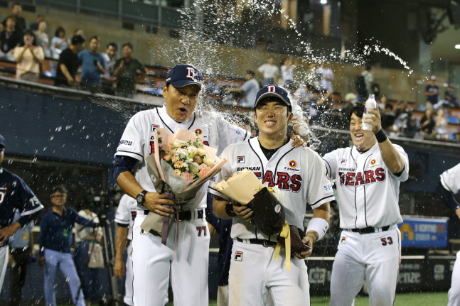 꽃다발을 들고 있는 이승엽 감독(왼쪽부터)과 주장 허경민에게 양석환이 물 세례로 축하를 전하고 있다. /사진=두산 베어스