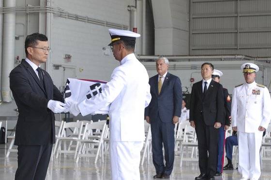 이근원 국방부 유해발굴감식단장이 25일(현지시간) 미국 하와이 히캄 공군기지에서 거행된 국군전사자 유해 인수식에서 태극기로 관포된 국군전사자 고(故) 최임락 일병의 유해를 유가족(조카)인 최호종 해군 상사에게 전달하는 모습. 국방일보.