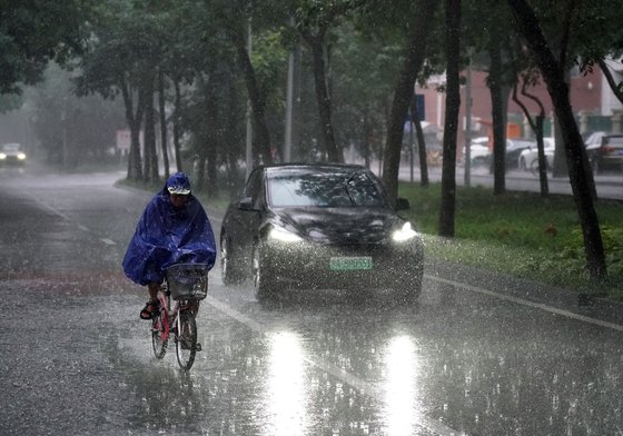중국 수도 베이징에 29일(현지시간) 태풍 '독수리'로 강한 비가 내리는 가운데 한 시민이 자전거를 타고 지나가고 있다. 신화=연합뉴스