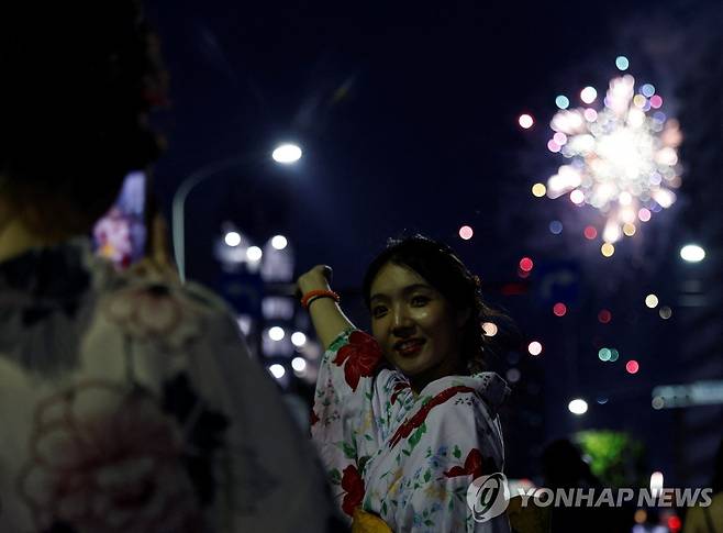 불꽃놀이 배경으로 기념사진 찍는 여성 (도쿄 로이터=연합뉴스) 일본 도쿄에서 스미다강 불꽃놀이가 열린 29일 한 여성이 밤하늘에 터진 불꽃을 배경으로 기념사진을 찍고 있다.