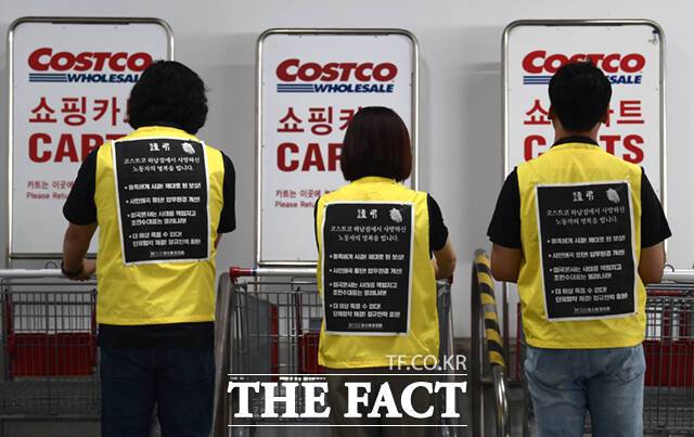 박건희 코스트코 지회장과 이소율 총무부장, 공경훈 부지회장(오른쪽부터)이 1일 코스트코 하남점 내 주차장 카트 앞에서 등을 보이며 서 있다. 이들의 등에는 지난 6월 사망한 김 씨를 추모하며 회사의 사과와 제대로 된 보상 등 책임을 촉구하는 문구가 적혀있다.