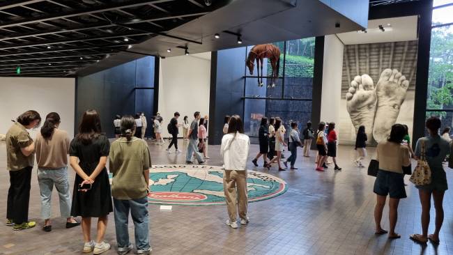 올해 상반기 열렸던 리움 미술관의 ‘카텔란:WE’ 전시에서 젊은 여성 관람객들이 작품을 감상하고 있다.  리움 제공