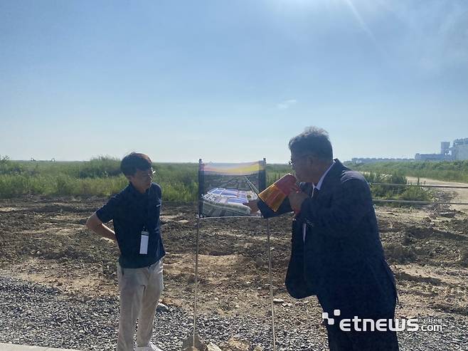 김상문 엔켐 이사(오른쪽)가 새만금 국가산업단지 5공구 이디엘 리튬염 생산공장 착공 부지에서 조감도를 가리키며 공장 신설 계획을 설명하고 있다.