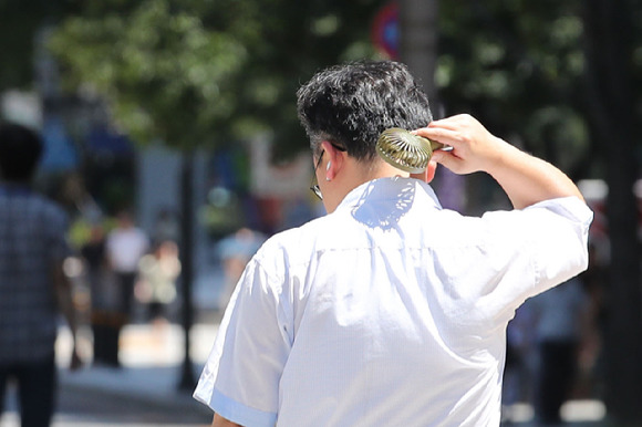 8일 오후 서울 종로구 광화문광장에서 한 시민이 선풍기를 목에 쐬고 있다. [사진=뉴시스]