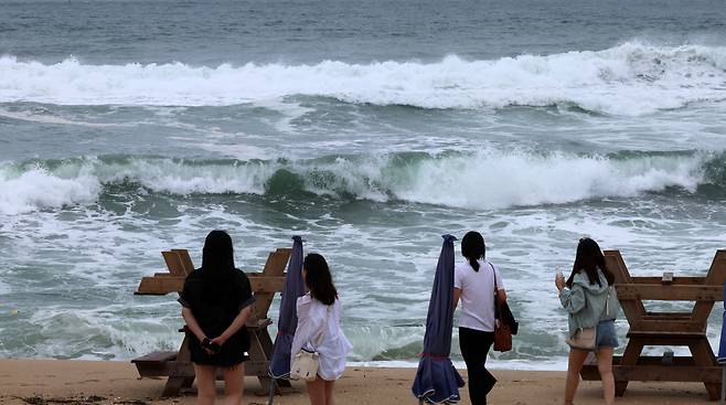 Tourists walk along Gangmun beach, Gangneung, Gangwon Province, as swimming has been banned due to high waves caused by Typhoon Khanun as it approaches, Tuesday. (Yonhap)