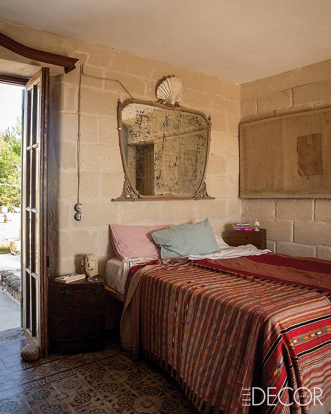 섬에 거주하는 석공의 도움을 받아 제작한 러스틱한 벽이 특징인 침실. 벽의 거울과 가구는 모두 빈티지 제품이다.