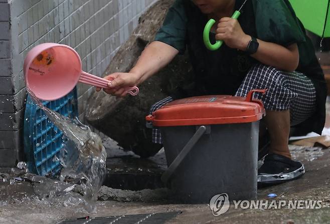 '비 더 오기 전에 물 퍼내야' (서울=연합뉴스) 김성민 기자 = 태풍 카눈이 서울에 근접한 10일 오후 서울 중구 동자동 쪽방촌에서 한 시민이 배수시설에 있는 물을 퍼내고 있다. 2023.8.10 ksm7976@yna.co.kr