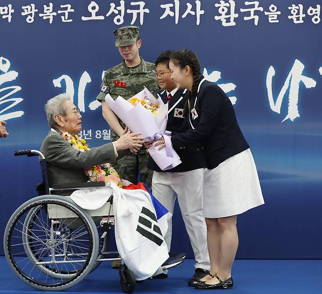 ‘한국광복군 제3지대’ 출신으로 일본에서 영구 귀국한 오성규 지사가 13일 서울 강서구 김포공항에서 열린 환국 환영 행사에서 역사어린이합창단 대표에게 꽃다발을 받고 있다. [연합뉴스]