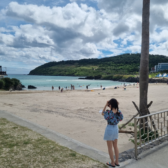 A tourist takes a picture of the scenery at Hamdeok Beach, Jeju City, Jeju. [KIM DONG-EUN]