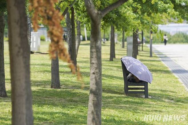 지난 6월 서울 영등포구 여의도 한강시민공원을 찾은 시민이 양산 아래서 휴식을 취하고 있다. &nbsp; 사진=임형택 기자