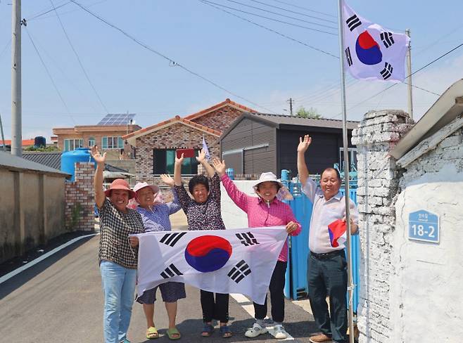 전남 해남군 황산면 산소마을에서 김행수 이장(오른쪽)과 주민들이 광복절을 하루 앞둔 지난 14일 마을에 있는 55개 국기게양대에 태극기를 새것으로 바꿔 달며 인사하고 있다. 해남군 제공