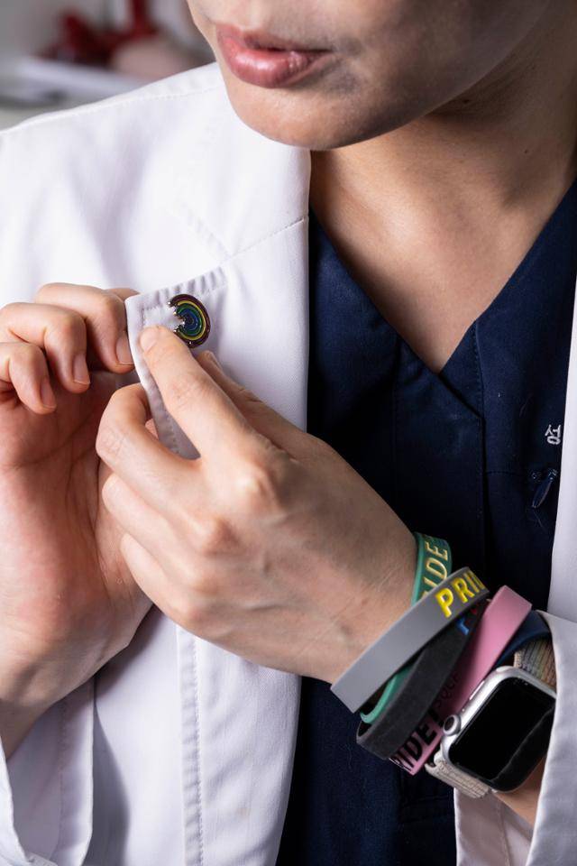 김결희 교수가 성소수자 엘라이임을 드러내는 무지갯빛 배지를 가운에 달고 있다. 팔목엔 역대 서울 퀴어퍼레이드 굿즈였던 팔찌들이 채워져 있다. han@hankookilbo.com