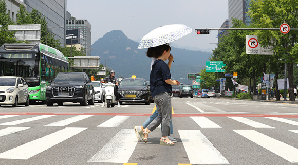 지난 14일 서울 중구 한 도로에서 시민이 양산을 쓰고 횡단보도를 건너고 있다.  [사진=뉴시스]