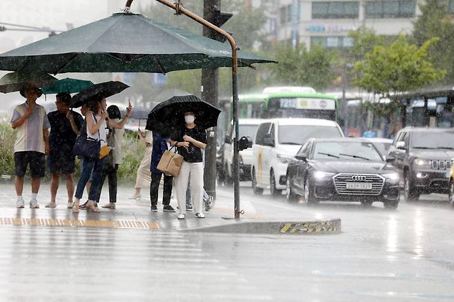 비가 내린 22일 오후 서울 종로구 광화문 네거리에서 시민들이 우산을 쓰고 횡단보도 신호를 기다리고 있다. /뉴시스