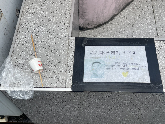 대전 중구 은행동 으능정이거리의 한 가게에 부착된 불법 투기 경고문 옆에 탕후루 종이컵과 꼬챙이가 놓여져 있다. 사진=최다인 기자
