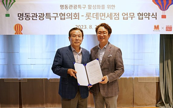 지난 28일 서울 중구 롯데면세점 명동본점에서 열린 '명동 지역 관광 활성화를 위한 업무협약' 체결식에서 김병희 명동관광특구협의회장(왼쪽)과 김주남 롯데면세점 대표이사가 기념촬영을 하고 있다. 롯데면세점 제공.