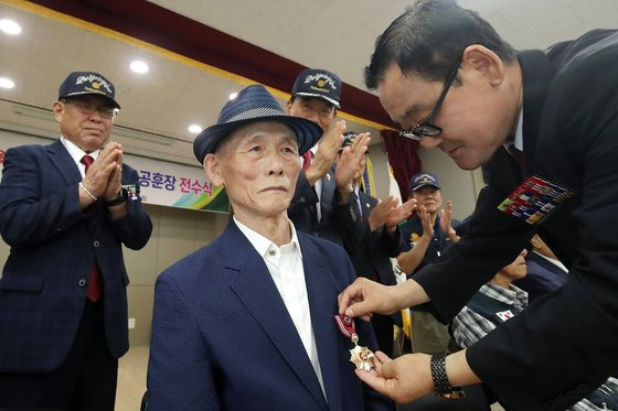 29일 오전 대구 달성군 보훈회관 대회의실에서 열린 '6·25참전용사 고(故) 이문용 병장 화랑무공훈장 전수식'에서 대한민국 무공수훈자회 대구시지부 임동호 달성군지회장(오른쪽)이 서훈 대상자 이문용 병장의 동생 이시용(77)씨 가슴에 화랑무공훈장을 달아주고 있다. 뉴스1