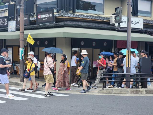 19일 일본 교토의 유명 사찰인 기요미즈데라 인근 거리에서 단체 관광객들이 노란 깃발을 든 가이드를 따라 길을 건너고 있다. 교토=박지영 기자