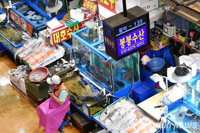 손님이 별로 없자 한 상인이 휴대폰으로 음악을 듣고 있다.