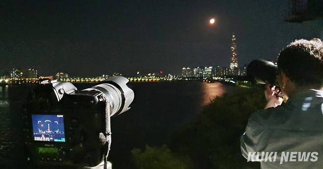 1일 밤 강남구 삼성동에 위치한 해맞이 공원에서 한 사진가가 떠오르는 수퍼블루문을 카메라에 담고 있다.