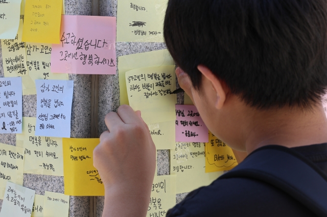2일 오전 한 어린이가 서울 양천구 소재 초등학교 앞에 마련된 교사 A씨의 추모 공간에 메시지를 남기고 있다. 연합뉴스