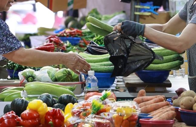 지난달 1일 서울 서대문구의 한 전통시장을 찾은 시민이 오이를 구매하는 모습. [사진 = 연합뉴스]