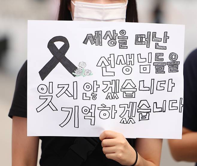 서울 서초구의 한 초등학교에서 숨진 교사의 49재이자 이를 추모하는 '공교육 멈춤의 날'인 4일 오전 서울 광화문광장 이순신 장군 동상 앞에서 열린 '공교육 멈춤의 날' 지지 기자회견에 참석한 한 참가자가 피켓을 들고 있다. ⓒ연합뉴스