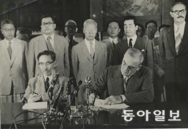 1953년 8월 8일 경무대에서 열린 한미상호방위조약 가조인식. 변영태 외무 장관과 존 포스터 덜레스 미 국무 장관(앞에 앉은 이들)이 서명하는 모습을 이승만 대통령(가운데)이 지켜보고 있다.  이승만대통령기념사업회