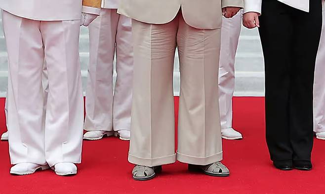 김정은(가운데) 북한 국무위원장이 통이 넓은 크림색 바지를 입고 피셔맨 샌들을 신은 모습. 그는 당뇨발을 앓고 있는 것으로 추정된다. 발이 화끈거리고 극심한 통증을 겪는 당뇨발 환자들은 발 볼이 넓고 통풍이 잘되는 특수 신발을 신는다.[조선중앙통신]