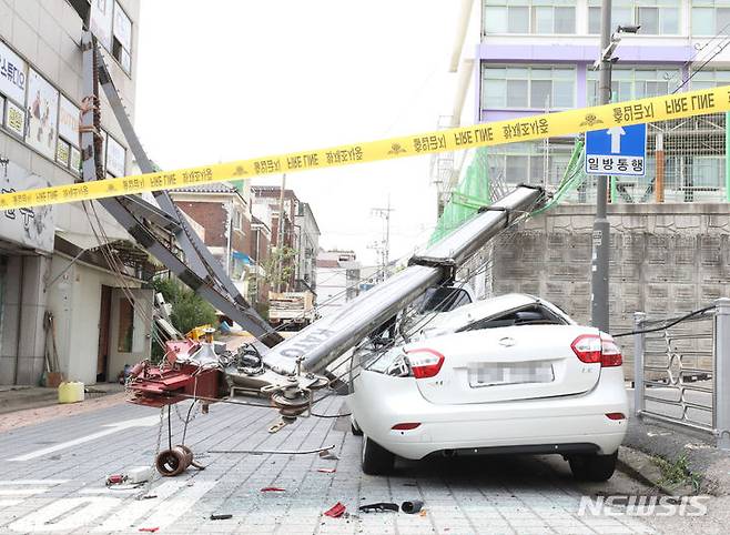 [인천=뉴시스] 전진환 기자 = 12일 오후 인천 남동구 한 초등학교에서 건물 내진 보강공사를 하던 13t 크레인이 지반 침하로 전도되어 있다. 이 사고로 학교 담장 밖 건물과 주차돼 있던 차량 3대가 파손됐다.  2023.09.12. amin2@newsis.com