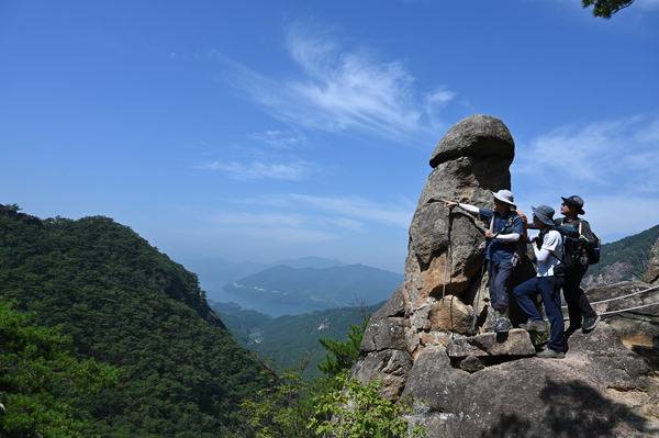 충북 제천시 금성면 동산 산행은 전국의 등산동호인이 불끈 솟은 남근석을 보려고 많이 찾는다. 충주호를 배경으로 선 남근석에서 청주에서 왔다는 이호중 씨 일행을 만났다. 인터넷에 올라가는 국제신문 근교산 애독자로 취재팀 부탁에 기꺼이 모델이 되어 주었다.