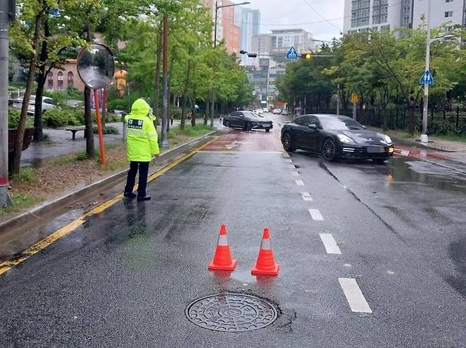 [부산=뉴시스] 호우경보가 발효된 16일 오후 부산 해운대구의 한 도로의 맨홀이 역류해 경찰이 인근 도로를 통제하고 있다. 2023.09.16. (사진=부산소방재난본부 제공) *재판매 및 DB 금지