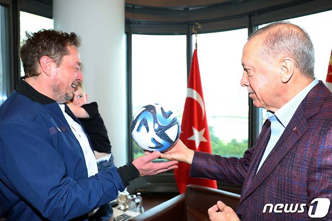 머스크가 에르도안 대통령에게서 축구공을 건네받고 있다. 여전히 아이를 왼팔에 안고 있다. 에르도안 대통령이 약간 뻘쭘한 모습이다. ⓒ 로이터=뉴스1 ⓒ News1 박형기 기자