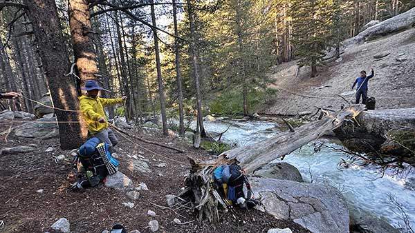 엄청나게 불어난 계곡물로 길이 사라져서 안전하게 통나무를 건너가기 위해 계곡 양쪽 나무에 로프를 매고 있다.