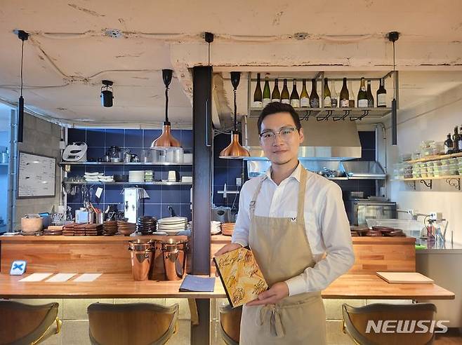 [부산=뉴시스] 이동민 기자 = 전지성 레썽스 오너 셰프. BTS 멤버의 사인이 담긴 메뉴판을 들고 있다. 2023.09.22. eastsky@newsis.com