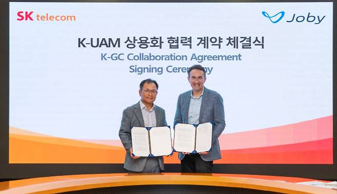 SK텔레콤은 글로벌 UAM 기체 제조사 조비와SK T타워에서 한국형 UAM 상용화를 위한 협력 계약을 체결했다. SK T타워에서 열린 협약식에서 하민용 SKT CDO(왼쪽), 에릭 앨리슨 조비 부사장(오른쪽)이 계약을 체결하고 기념촬영을 하고 있다. 사진=SKT